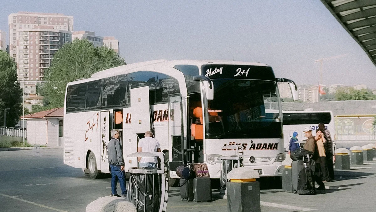 Passageiros com bagagens ao lado de um ônibus de viagem em uma plataforma