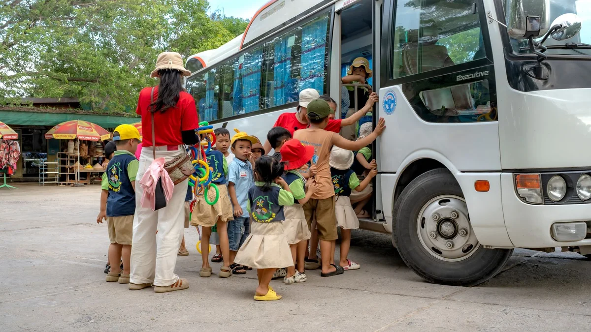 Crianças acompanhadas por adultos embarcando em um ônibus