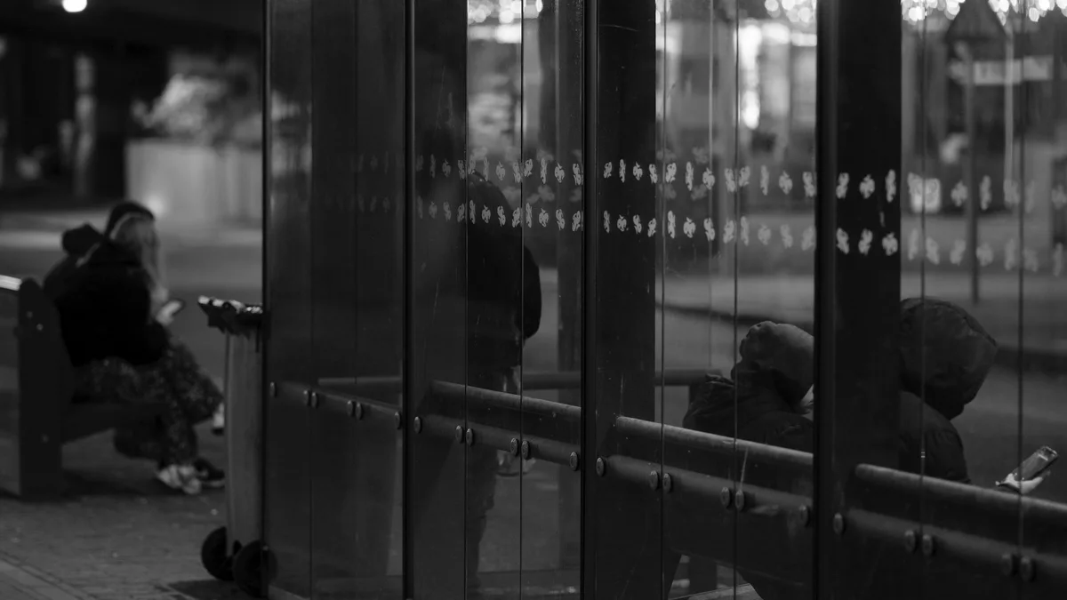 Passageiros esperando à noite em um abrigo de vidro